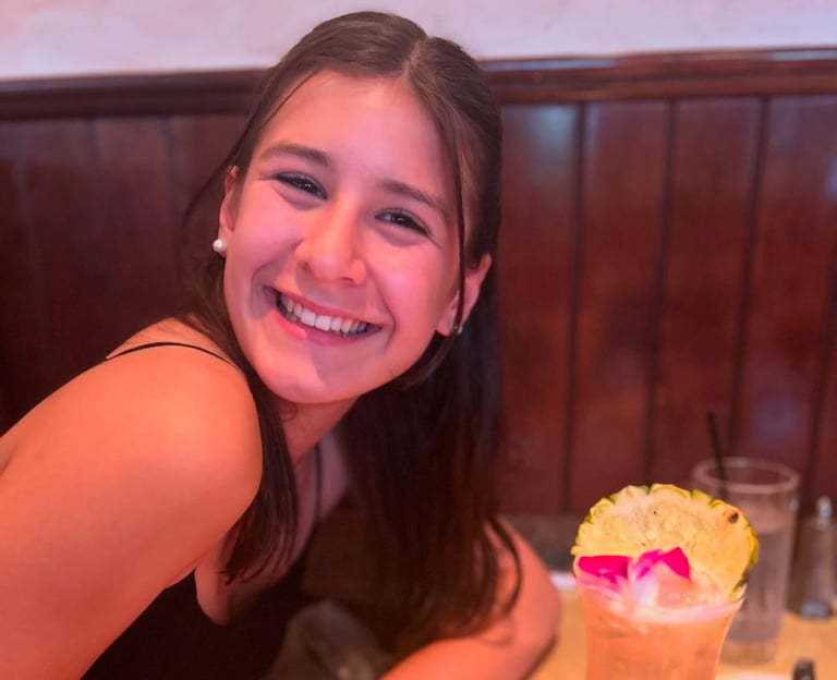 A girl sitting at a table drinking a drink