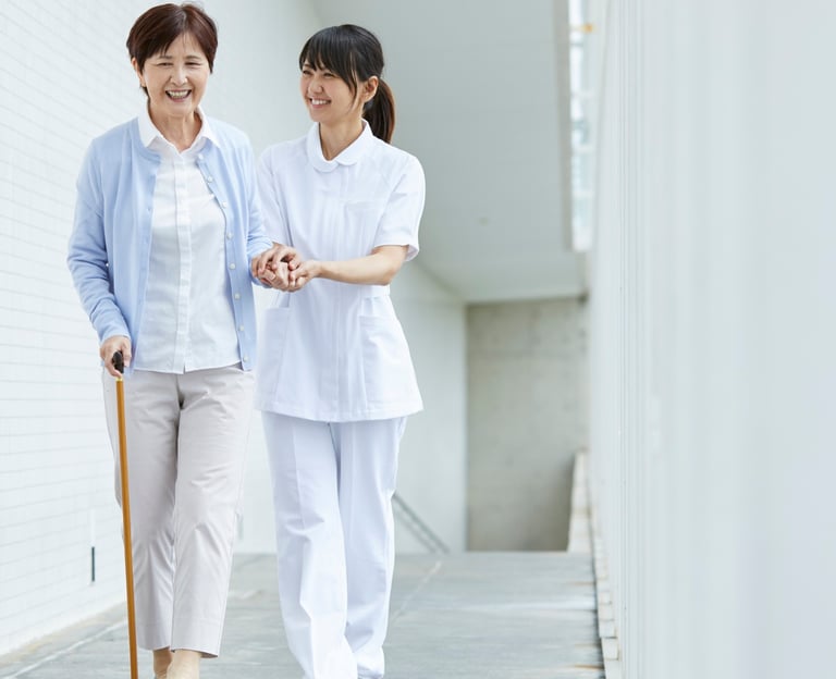 une femme âgée s'appuyant sur sa canne aidé d'une soignante esquifs quelques pas.