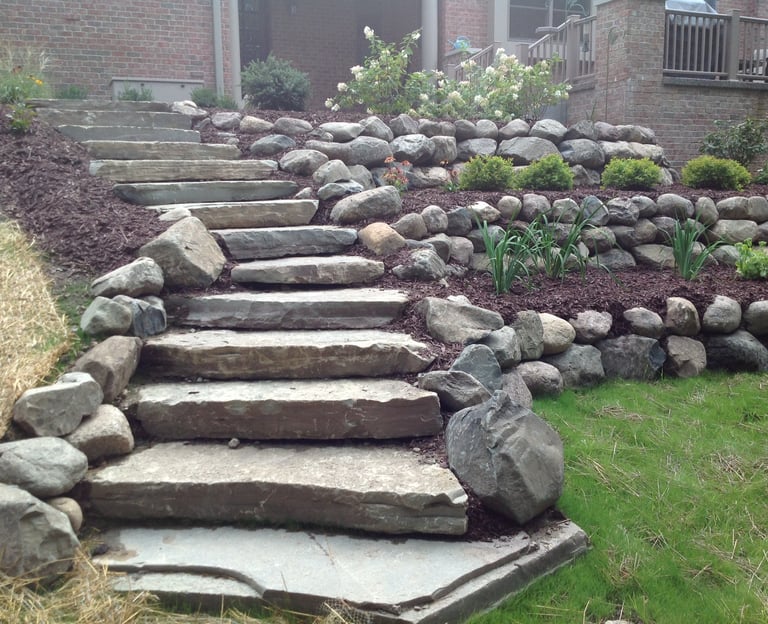 Leppek Landscape designed and installed steps, retaining wall, boulders, shrubs and trees. 