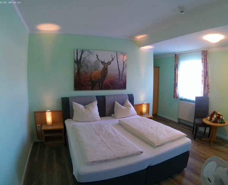Modern hotel bedroom featuring a double bed, deer wall art, and ambient bedside lighting.