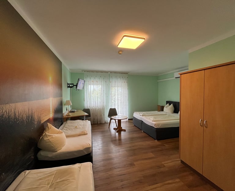 Modern hotel room with wood floors, double bed, sunset wall mural, and wardrobe.