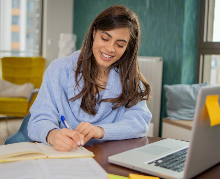 a woman sitting at a desk with a laptop and notebook