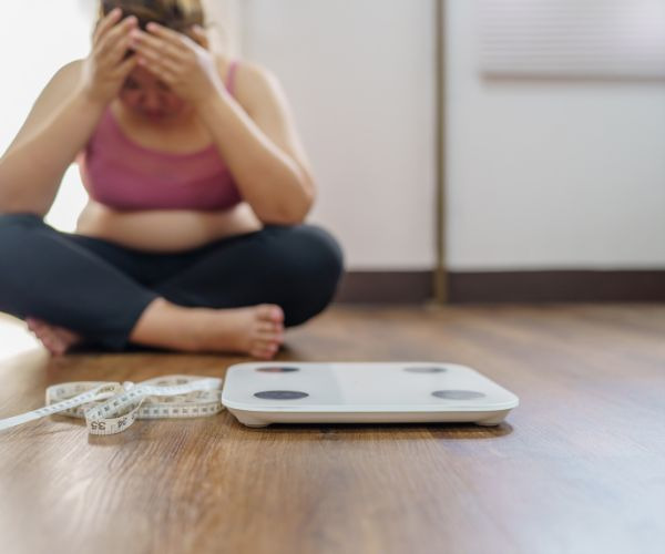 woman sitting on the floor with a weight scale