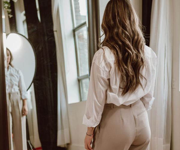 a woman in a white shirt and pants standing in front of a mirror