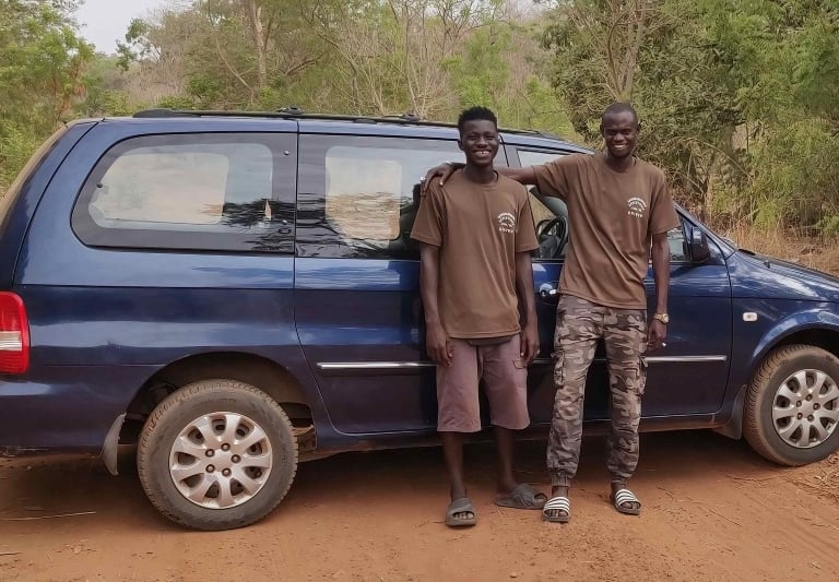 Twee gidsen van Birding Adventures Gambia & Senegal naast een blauwe minibus.