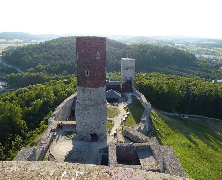 Widok z drona na zamek w Chęcinach. Środek lata. Dużo zielonego lasu w około.