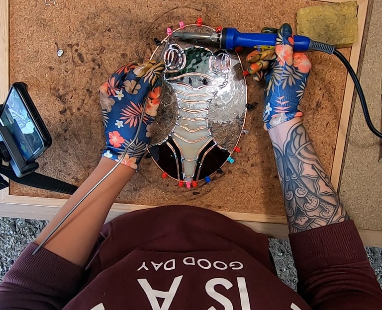 a person who is soldering a sun catcher, stainglass
