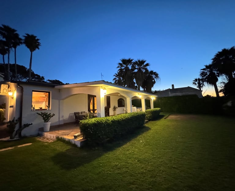 Luxury beachfront villa in Siracusa, Sicily at sunset with palm trees and manicured garden