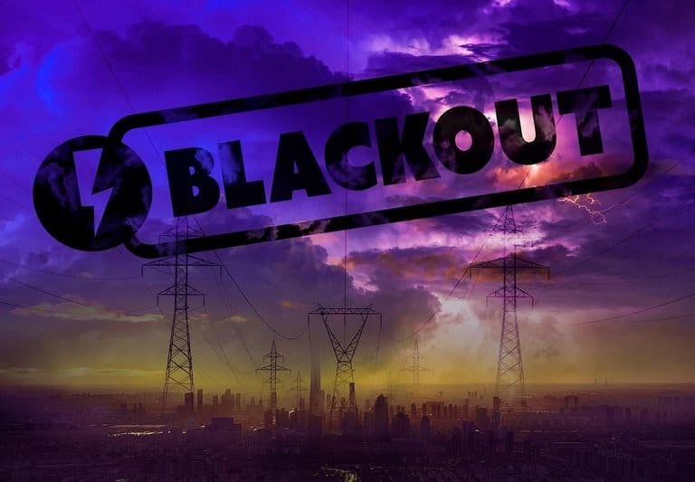 Skyline einer Stadt unter  Stromleitungen und großem Blackout-Schriftzug (Stromausfall).