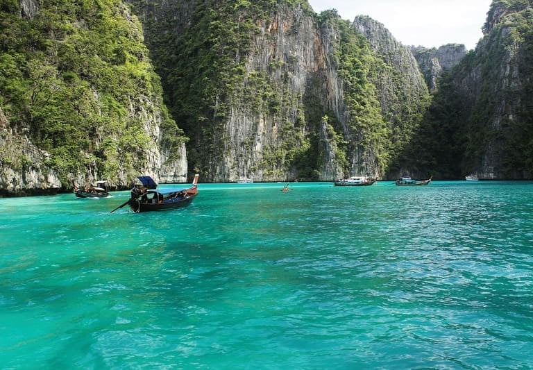 Traditionelle Longtail-Boote auf türkisfarbenem Wasser in der Pileh-Lagune auf den Phi-Phi-Inseln