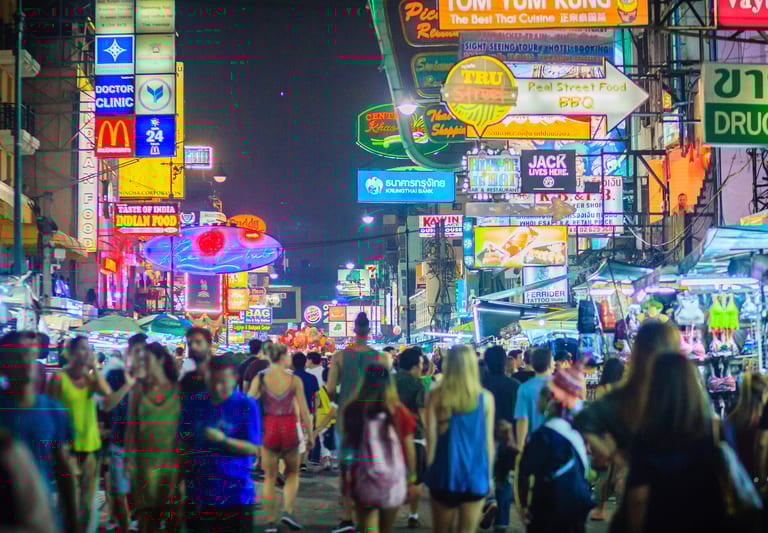 Nachts ein überfüllter Neon-Straßenmarkt in Bangkok, Thailand, mit leuchtenden Schildern