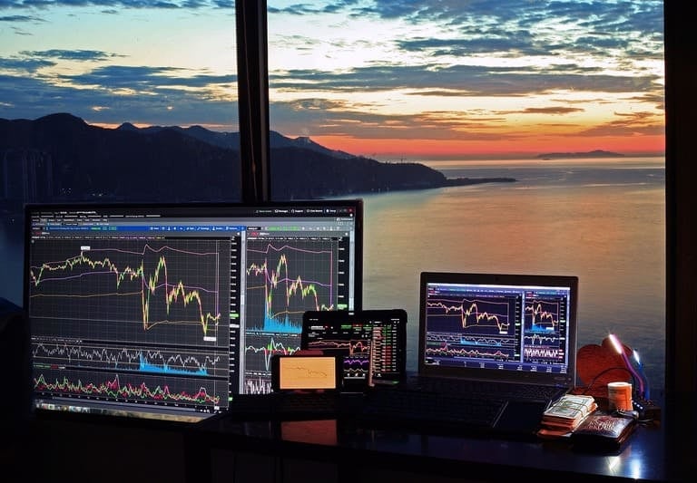 Börsenhandelsarbeitsplatz mit mehreren Monitoren, die Marktdaten und Charts anzeigen