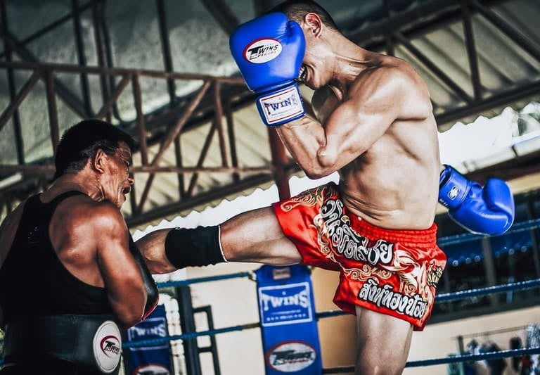 Professioneller Muay-Thai-Kämpfer setzt in einem Boxring einen kraftvollen Roundhouse-Kick gegen
