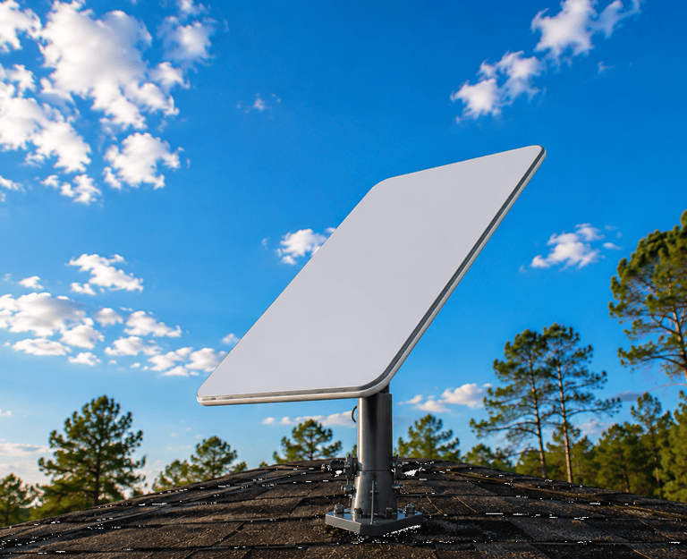 A Starlink satellite internet dish mounted on a residential roof under a clear blue sky with pine trees.