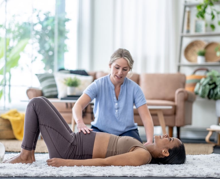 a woman in a blue shirt is helping another woman with a pelvic floor stretch