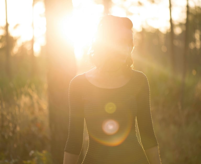 woman in forest with sun glistening representing subtle energy healing