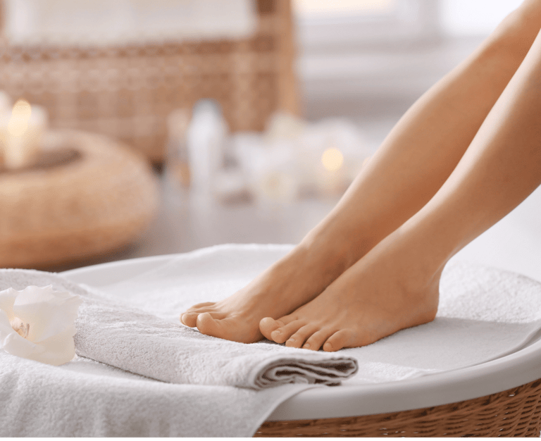 Verzorgde voeten rustend op een handdoek met sfeervolle kaarsen op de achtergrond bij Medisch Pedicure Grote Berg.