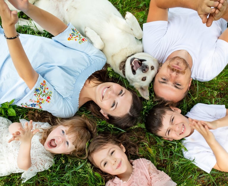 Eine Familie mit Hund liegen glücklich auf der Wiese