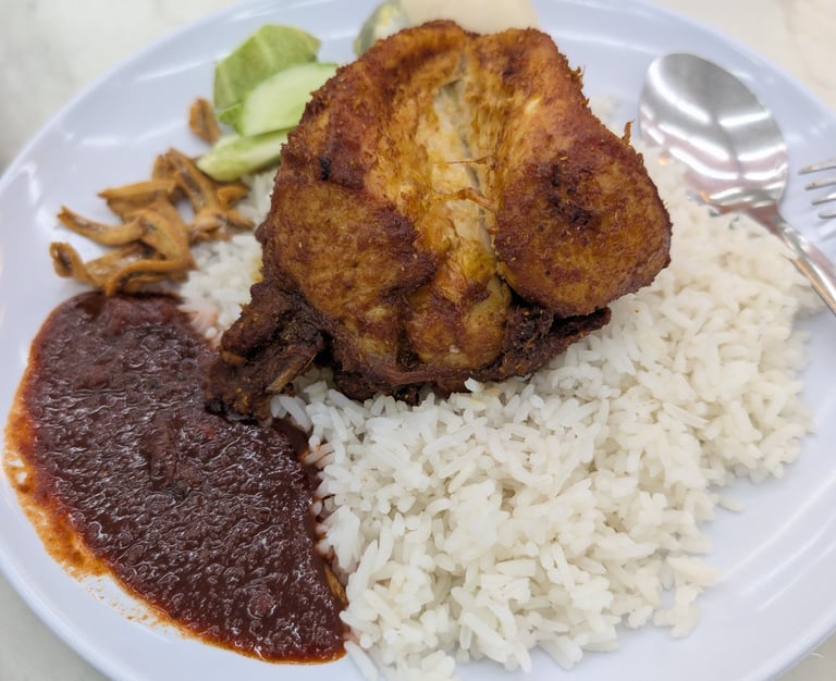 Malaysian Nasi Lemak plate with crispy fried chicken, coconut rice, spicy sambal, and anchovies.