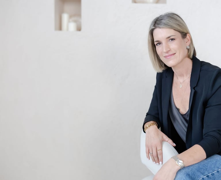 Yvonne seated in a therapy office, neutral background, relaxed portrait.