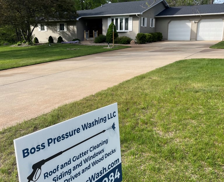 Boss Pressure Washing LLC yard sign in front of a freshly cleaned driveway and home.