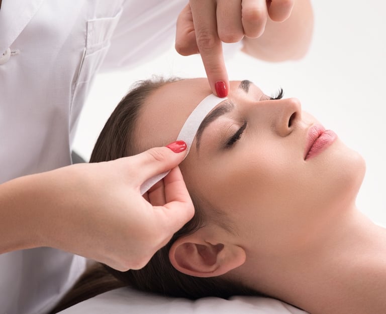 Una mujer está en el salón recibiendo un tratamiento de cera facial.