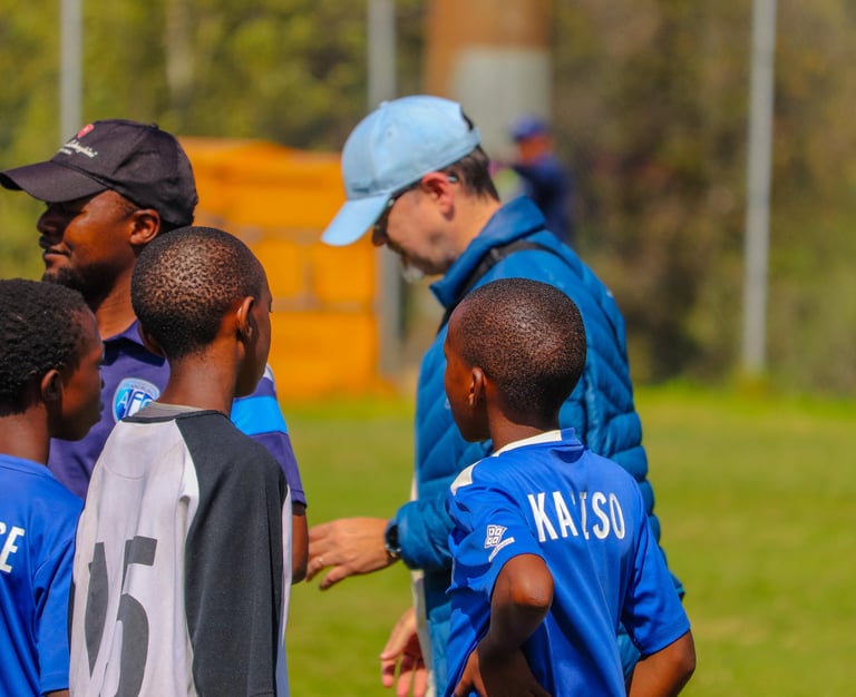 a man in a blue shirt is talking to a group of young boys
