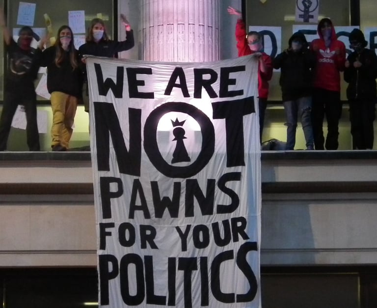 Activists standing on top of NHS England offices with a banner "we are not prawns for your politics"