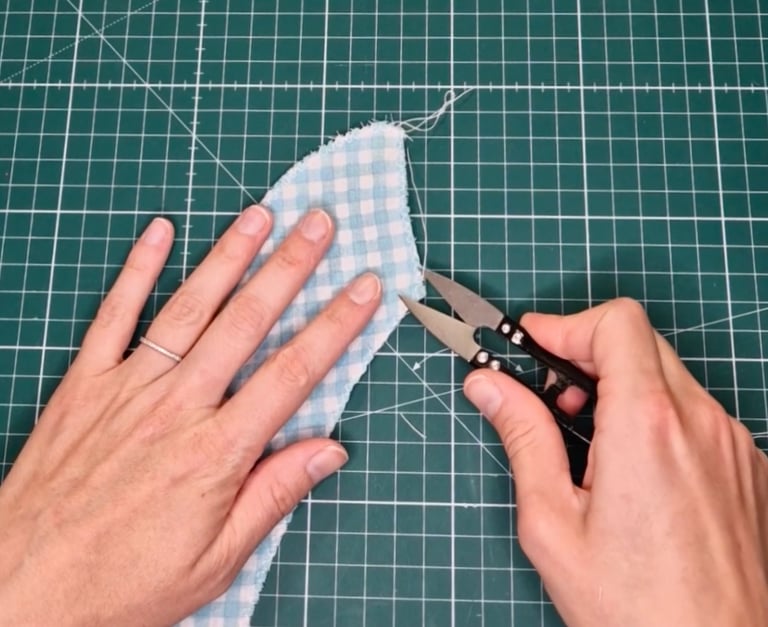 a person cuts a loose thread from a piece of fabric with thread cutters