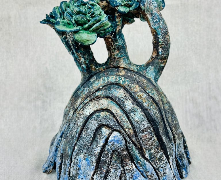 A ceramic plant-like sculpture glazed in green, blue and brown tones