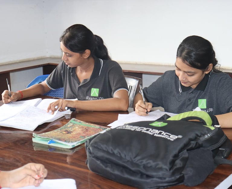 Students in Resonance uniforms studying and writing notes during a classroom session.