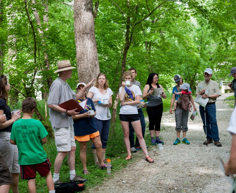 A circle of people stopped on a trail listening to the guide speak