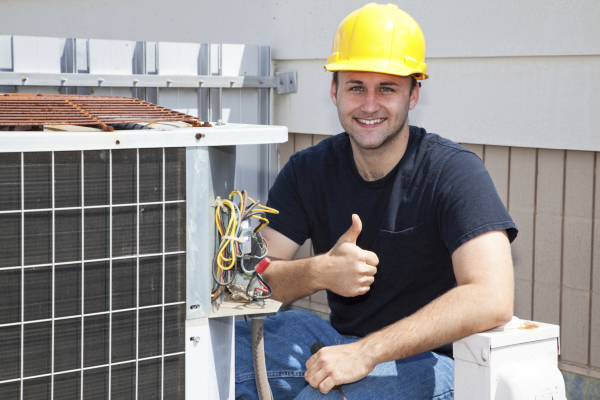 a man in a hard hat and a yellow helmet fixing a broken air conditioning unit