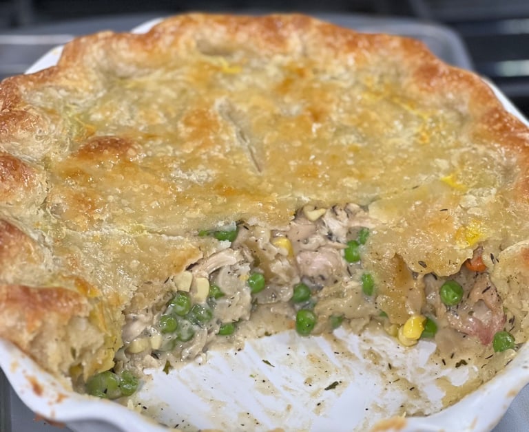 A golden brown homemade chicken pot pie with a flaky crust, filled with peas, corn, and creamy gravy.
