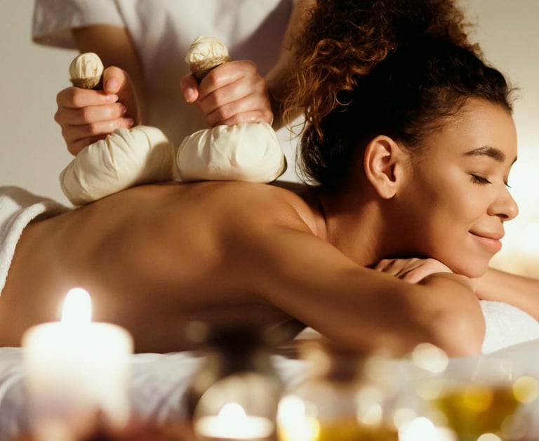woman getting massage with bags of organic herbs