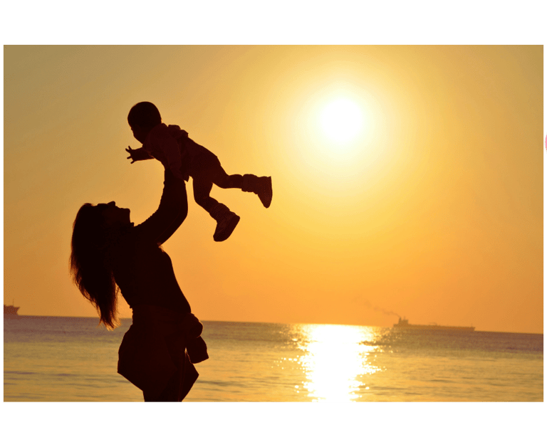 Photo montrant une mère soulevant son enfant sur fond de coucher de soleil