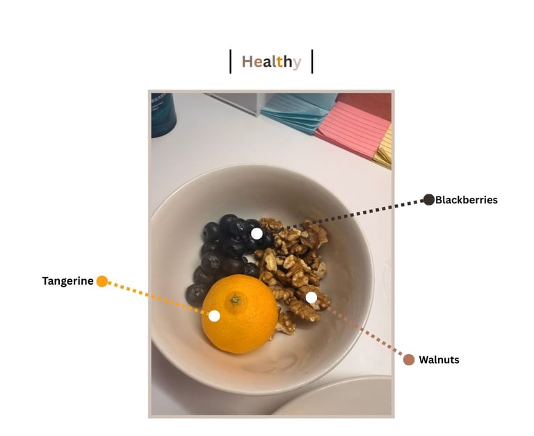A healthy snack bowl containing a fresh tangerine, walnuts, and blackberries.