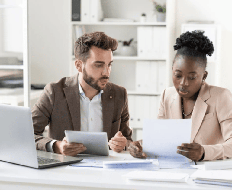 White male at a desk with a Black female looking over some paperwork