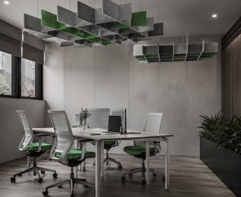 Modern office with ergonomic green chairs and hanging acoustic ceiling baffles for sound absorption.