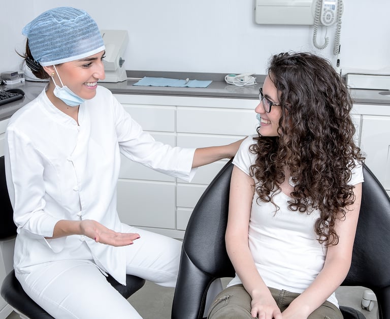 una mujer con camisa blanca y un dentista con bata blanca en una clínica dental