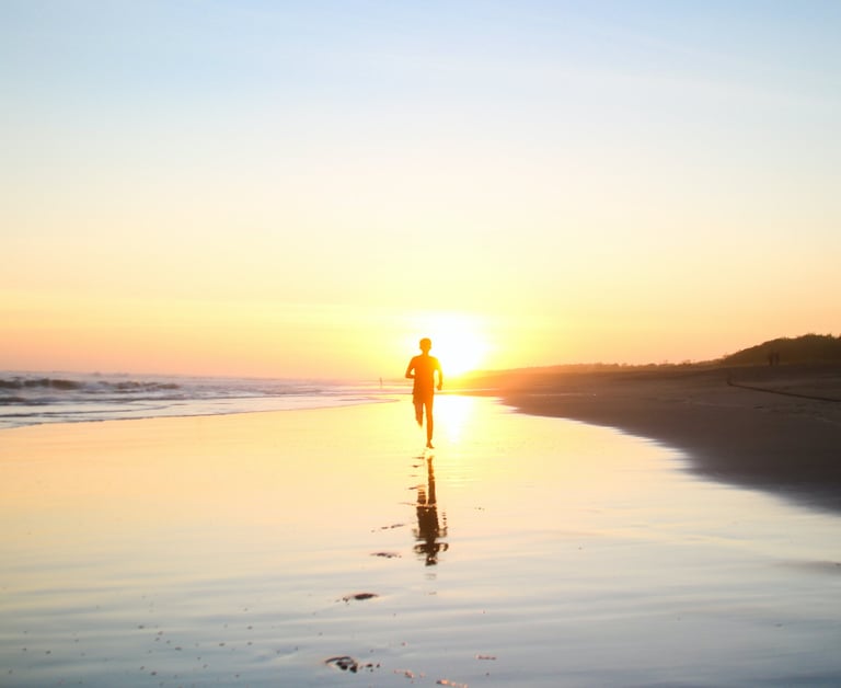 a person walking on a beach at sunset
