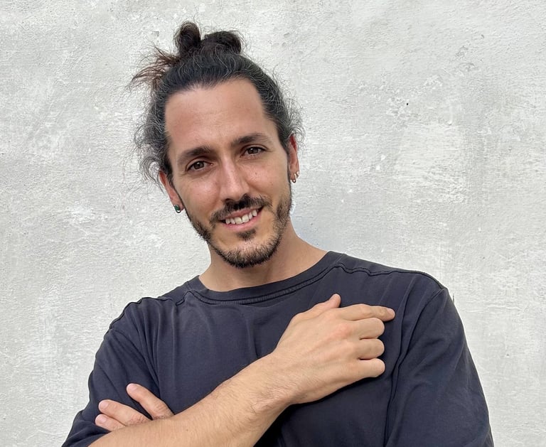 Borja Llegó posando de brazos cruzados frente a una pared gris, creador de contenido de viajes y gas