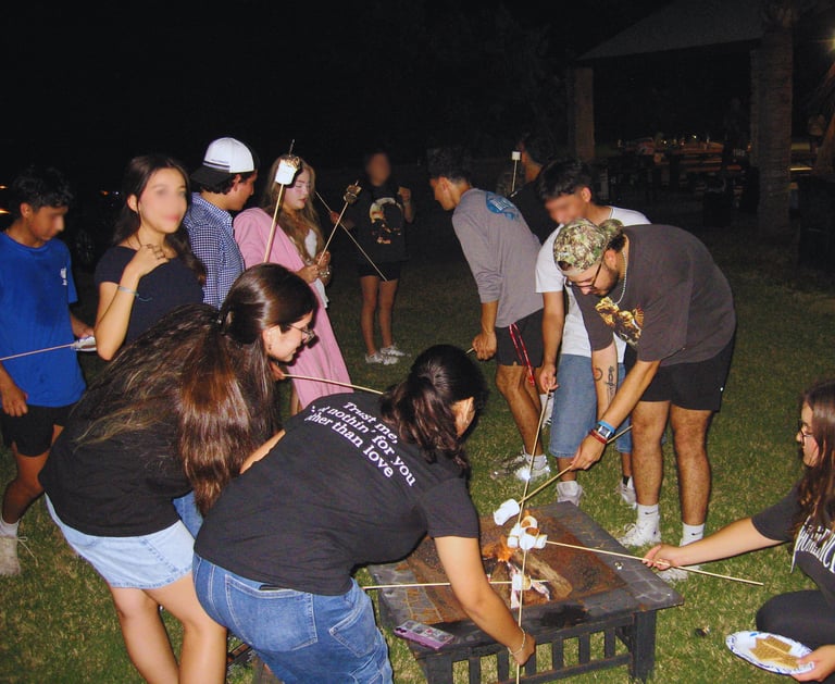 With young people roasting marshmallows outside by a campfire.