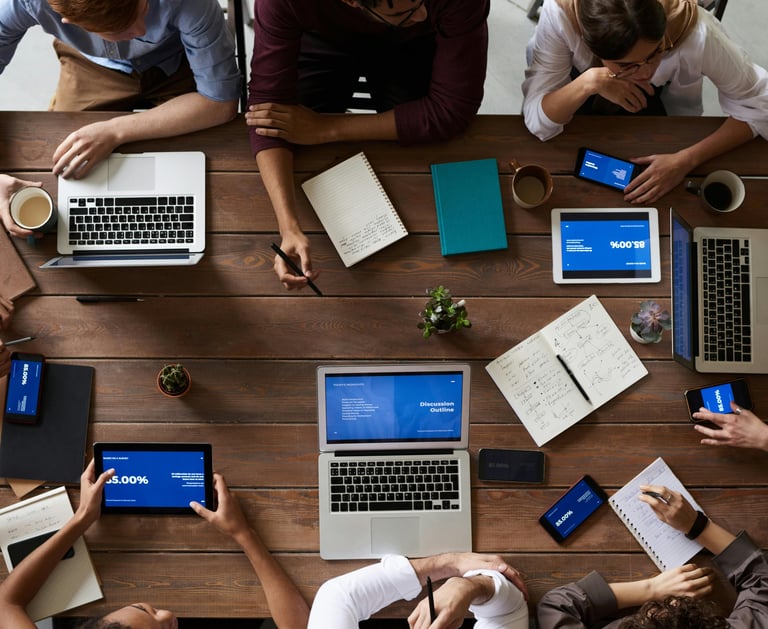 a group of people sitting around a table with laptops