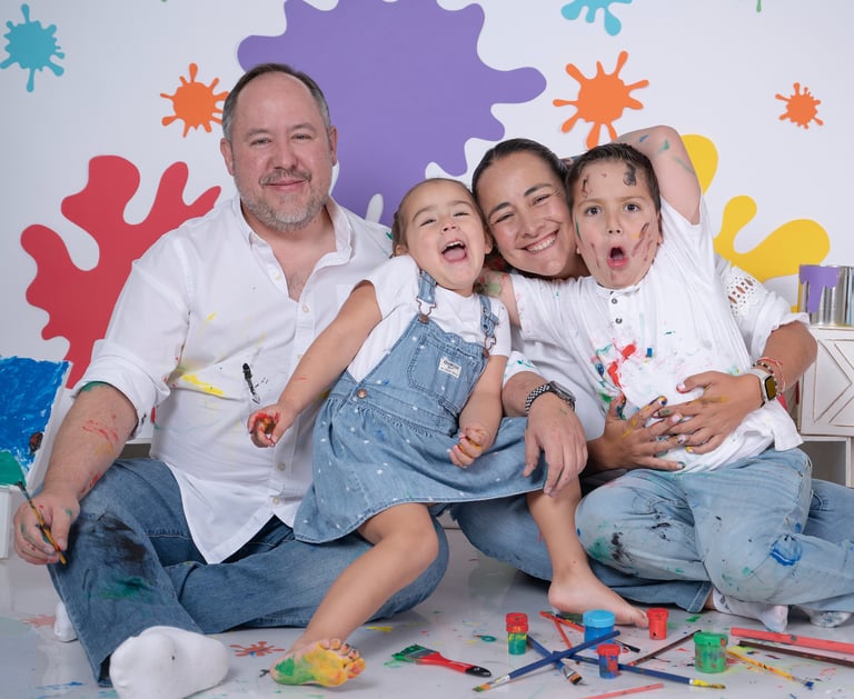 a family posing for a photo in front of a wall with paint splatters