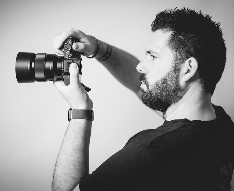 Portrait en noir et blanc de Cyril Steau, photographe à Paris, en pleine prise de vue avec un appareil photo professionnel.
