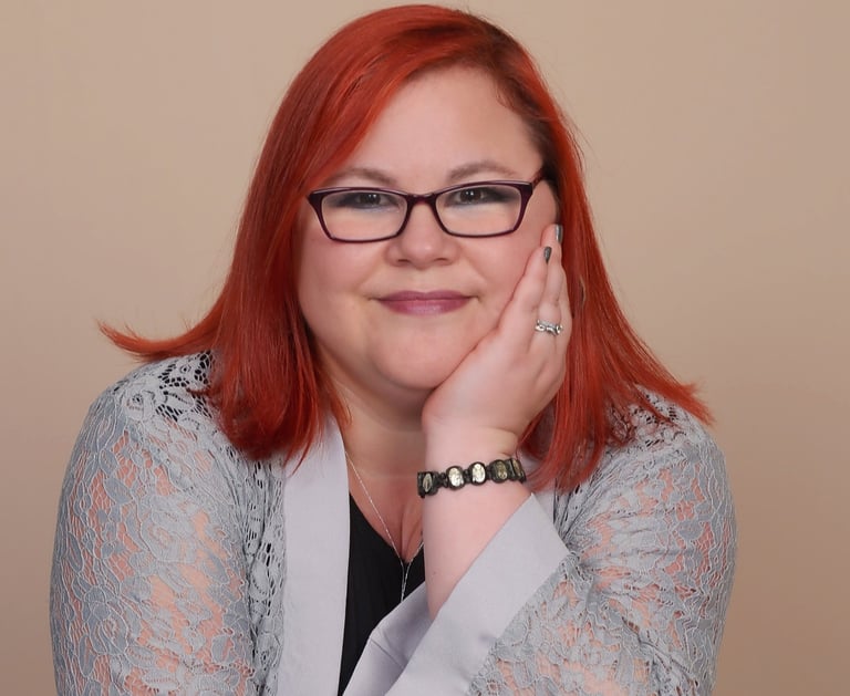Elizabeth Pressler smiles as she leans casually on the back of a chair.