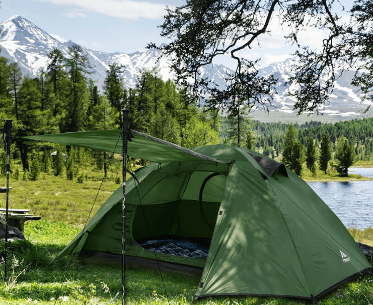 a tent pitched up in a field with a picnic table and chairs