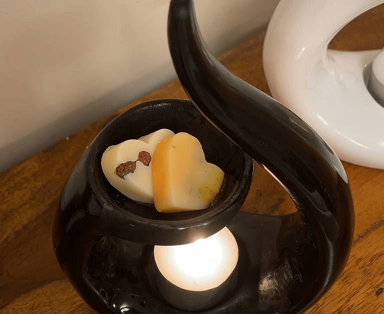 a black swirl ceramic wax burner with 2 heart shaped wax melts in the dish