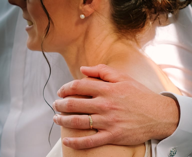 Marié tenant l'épaule de la marié avec sa bague au doigt